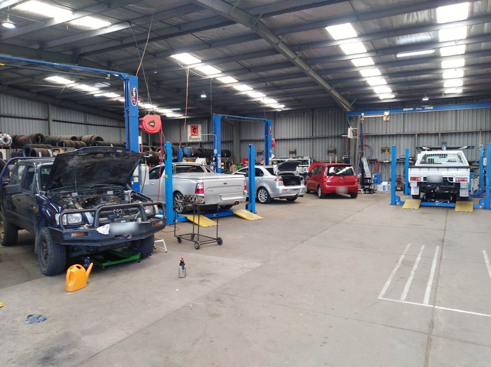 Inside the Thomson Valley Service Centre workshop, with cars and utes up on the blue hoists and tyres racked along the back wall